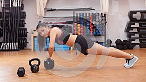 Woman sports push up on kettlebell