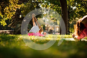 Woman in sportsuit practice yoga poses in the park