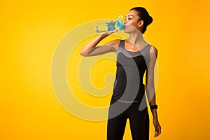 Woman In Sportswear Drinking Water Standing In Studio