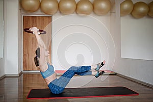 A woman in sportswear is exercising with a Pilates ring in the gym. Copy space