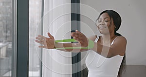 Woman in sportswear exercising with rubber resistance band