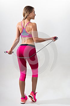 Woman in sportswear holding a rope in his hands. White background. Studio.