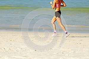 Woman in sportswear jogging on beach.