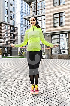 Woman in sportswear jumps rope outdoors