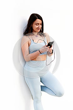 Woman in sportswear looks ar her phone on a white background