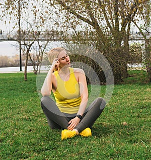 A woman in sportswear is resting after doing sports or yoga on city street. A healthy active lifestyle in modern city