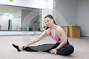 Woman in sportswear stretching on the floor and smile