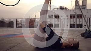 Woman in sportswear stretching and warm up before doing yoga on the rooftop in the evening when the sun set. Self care and health