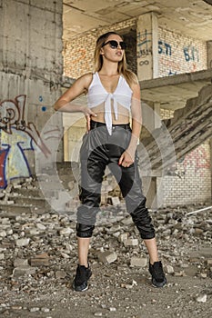 Woman in sporty clothes posing at abandoned construction site