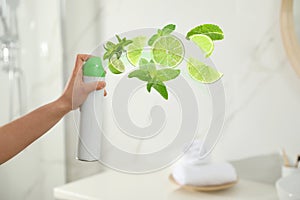 Woman spraying air freshener in bathroom. Lime and minty aroma