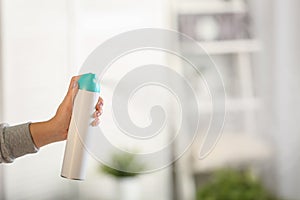 Woman spraying air freshener at home