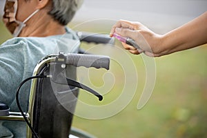 Woman is spraying alcohol,disinfectant spray on wheelchair handlebar hand,prevent infection,pandemic of Covid-19,spread of