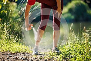 Woman spraying insect repellent against mosquito and tick on her leg