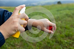 Woman spraying insect repellent at her hand. Woman using anti mosquito spray outdoors at hiking trip