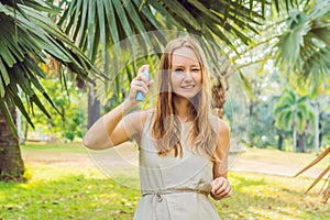 Woman spraying insect repellent on skin outdoor