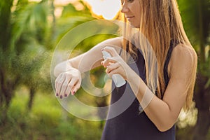 Woman spraying insect repellent on skin outdoor