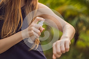 Woman spraying insect repellent on skin outdoor