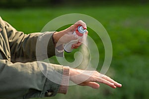 woman spraying insect repellent to hand at park