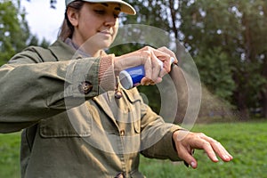 woman spraying insect repellent to hand at park