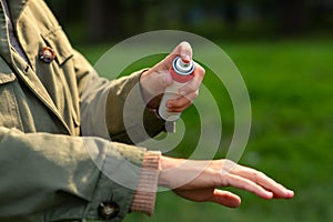 woman spraying insect repellent to hand at park