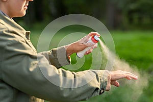 woman spraying insect repellent to hand at park