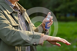 woman spraying insect repellent to hand at park