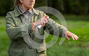 woman spraying insect repellent to hand at park