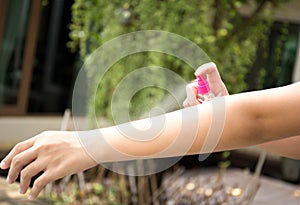 Woman spraying insect repellents on skin in the garden