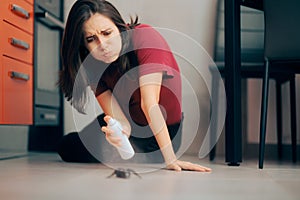 Woman Spraying with Insecticide Over an Ant on the Kitchen Floor