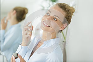 Woman spraying perfume on neck