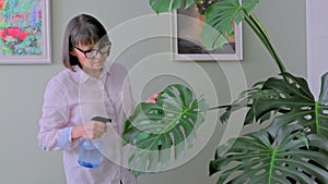 Woman spraying potted plants with water from a spray bottle