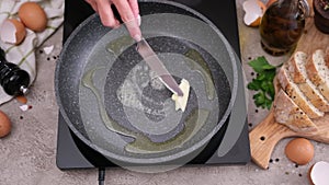 Woman spreading butter on the hot frying pan with knife