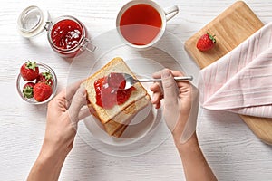 Woman spreading strawberry jam on toast bread