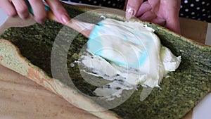 A woman spreads cream with biscuit cake with the addition of spinach and mint. The process of making Swiss roll