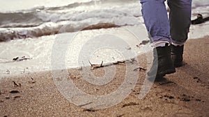 Woman in spring walks by sand to sea. Girl runs from water. Cinematic slow motion shot. Moving camera