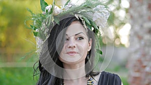 Woman in the spring. A wreath of meadow grass and flowers is worn on the brunette`s head. White peonies adorn the head
