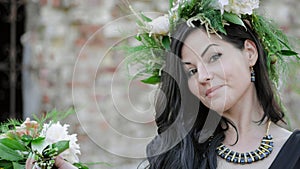 Woman in the spring. A wreath of meadow grass and flowers is worn on the brunette`s head. White peonies adorn the head