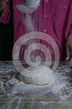 The woman sprinkles flour dough from the fullness for sifting flour, flour falls on the dough, a beautiful scattering of flour.