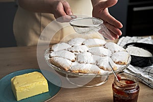 Woman sprinkling and decorating cookies with powdered sugar