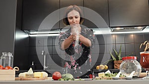 Woman sprinkling flour on table in kitchen, clapping her hands filled with flour. Female working with dough and flour, clapping ha