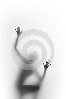 Woman squatter, and climb. Human body silhouette can be seen blurred behind a diffuse surface, only hands, palms and fingers are s