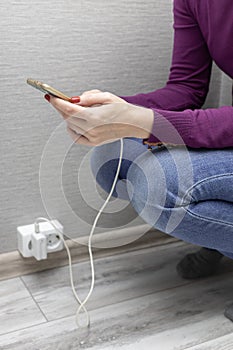 woman squatting holding phone connected on charger