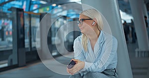 Woman squatting listening to music in subway. Boring waiting in noisy subway headphones earphones drown out annoying