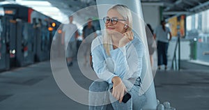 Woman squatting listening to music in subway. Caucasian woman enjoys favorite music in wireless headphones in noisy