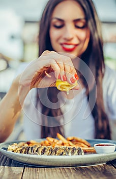 Woman squeeze lemon on portion of fish in a restaurant