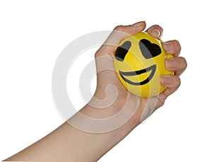 Woman squeezing antistress ball with funny face on white background, closeup