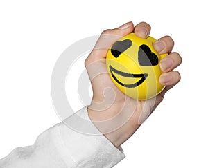 Woman squeezing antistress ball with funny face on white background, closeup