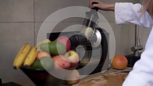 Woman squeezing apple or pear juice in the morning using juicer at kitchen