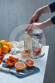 Woman Squeezing Blood Oranges in Vintage Juicer to Make Juice