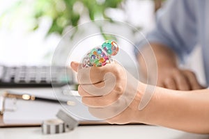 Woman squeezing colorful slime in office. Antistress toy